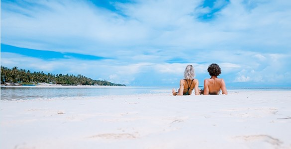 Två personer liggandes på rygg på en vit sandstrand