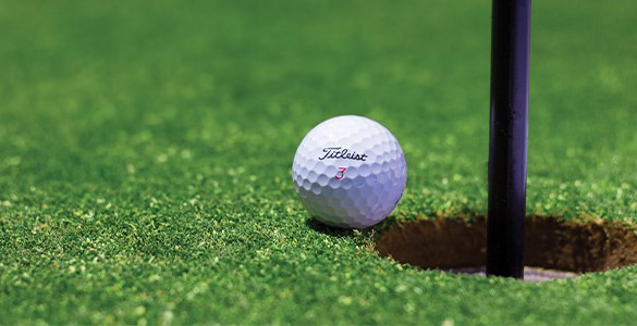 Golfboll vid hål på golfbana