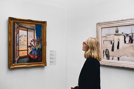 Kvinna tittar på tavlor på konstutställning