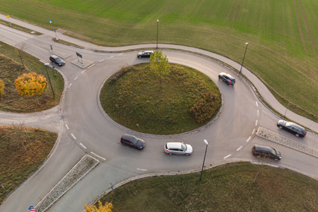 Flygfoto över en bilväg med en rondell med bilar i 