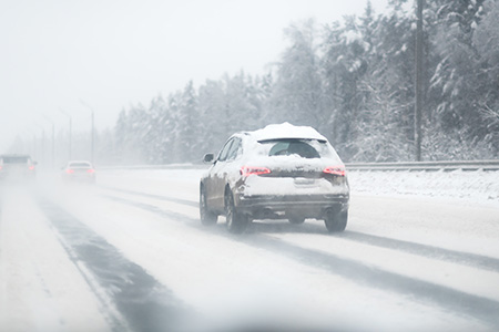 En snötäckt bil som kör på väg i vinterväglag