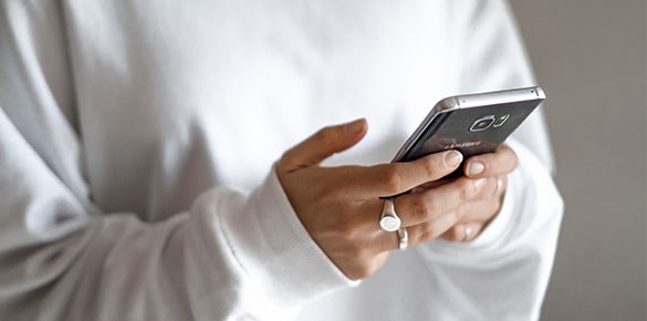 Person i vit tröja som håller i en smartphone