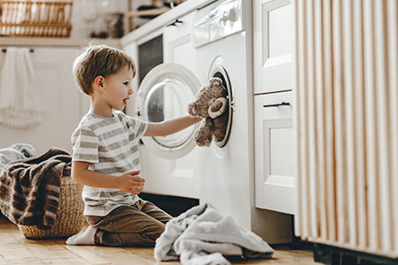 Pojke stoppar in gosedjur i tvättmaskin