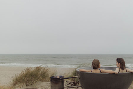 Två vänner i lyxig badtunna på strand