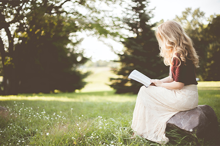 Kvinna som läser en bok utomhus