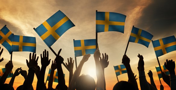 Bild på svenska flaggor som viftar i solnedgång