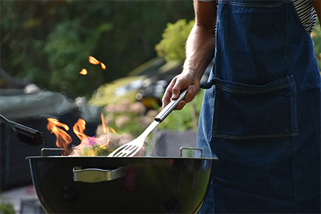 Man som står och grillar med en kolgrill