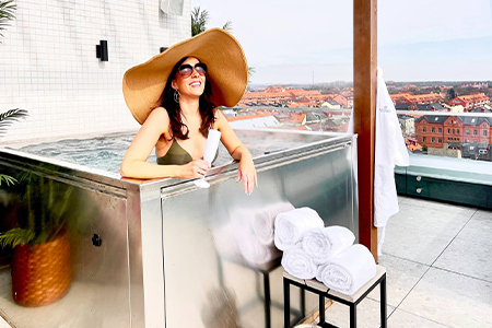 Glad kvinna med solhatt i jacuzzi på Hotell Fritidens takterrass i Ystad
