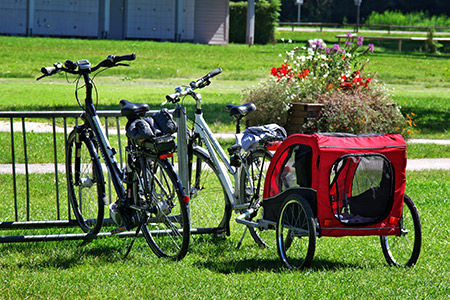 Två cyklar vid ett cykelställ varav den ena är utrustad med en cykelvagn 