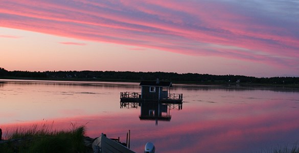 Bastuflotte på sjö i rosa solnedgång