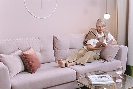 Äldre kvinna läser bok i en soffa