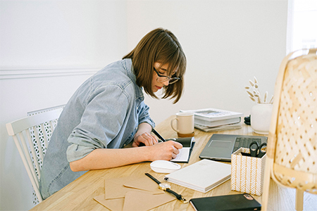 Kvinna som sitter vid ett skrivbord och skriver listor