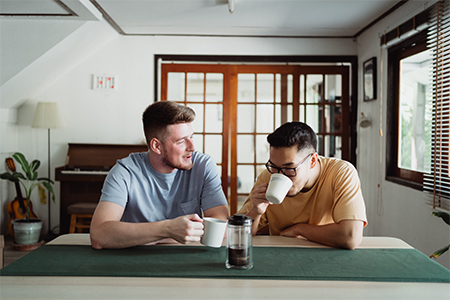 Två manliga vänner som sitter och dricker kaffe