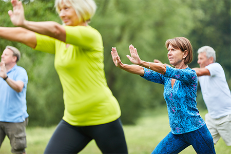 Grupp med människor som utövar qigong utomhus