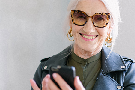 Äldre, leende kvinna med solglasögon i cat eye-modell