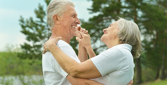 Äldre, leende par dansar tätt en sommardag