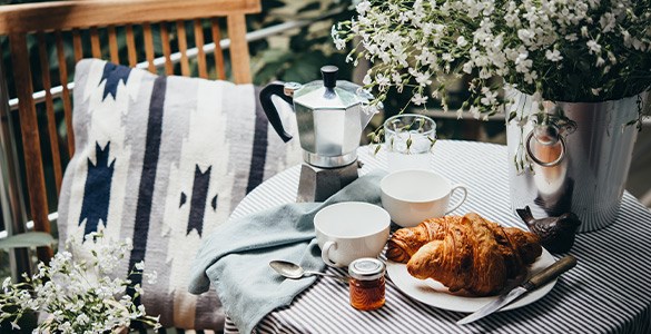 Litet balkongbord med blommor och fika