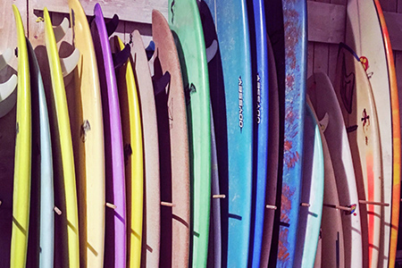 Flera surfbrädor i olika färger längs vägg i surfshop