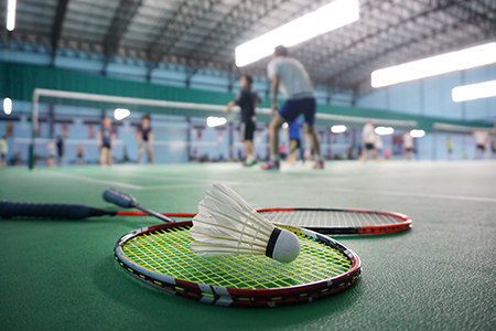 Två badmintonrack ligger på golvet med en badmintonboll ovanpå