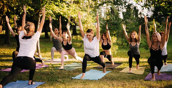 Människor tränar yoga utomhus bland träd