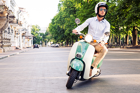 En grön och vit moped kör på en stenlagd gata i stadsmiljö