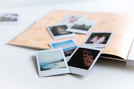 Små pappersfotografier utspridda på en tomt fotoalbum