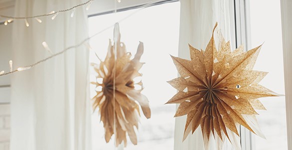 Två bruna julstjärnor gjorda i papper hänger i ett fönster