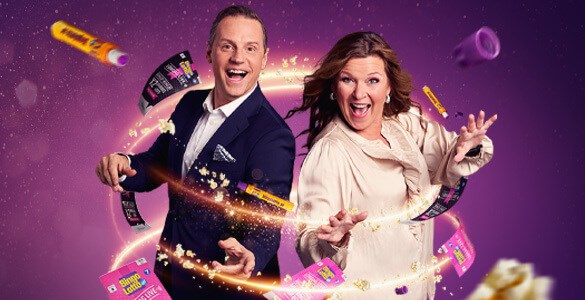 Lotta Engberg och Stefan Odelberg står och ser upprymda ut i en guldig virvel där det flyger runt popcorn, bingolotter och duttpennor. 