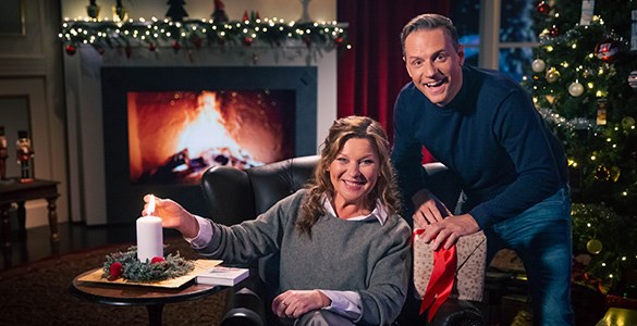 Lotta Engberg och Stefan Odelberg tänder ett ljus i en julpyntad bingolotto-studio