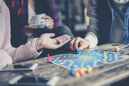 Tre personer sitter runt ett bord och spelar ett brädspel