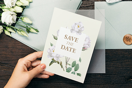 En hand håller i ett kort med texten save the date