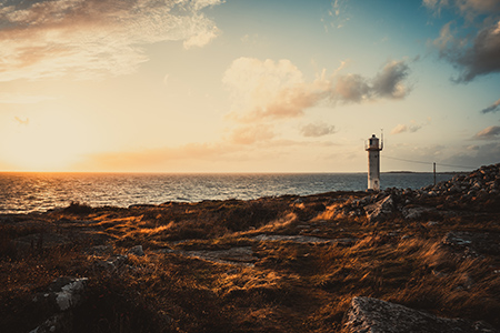 En liten fyr står på klippor intill havet