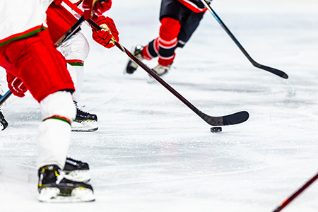 Närbild på ben och fötter på hockeyspelare på is under spel