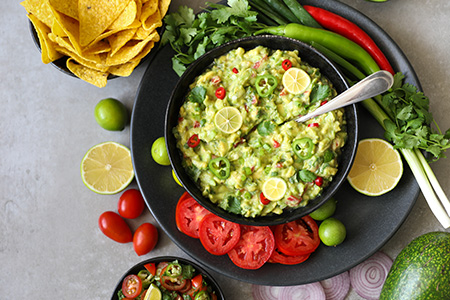 En skål med guacamole och tillbehör fotograferad ovanifrån