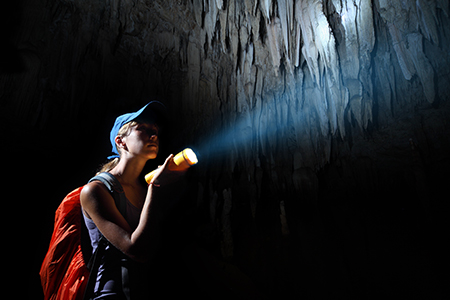 En kvinna lyser med en ficklampa i en mörk grotta