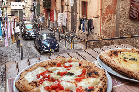 Två pizzor på ett bord i en liten italiensk gränd