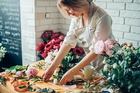 Leende kvinna skapar blomsterarrangemang i blomsterbutik