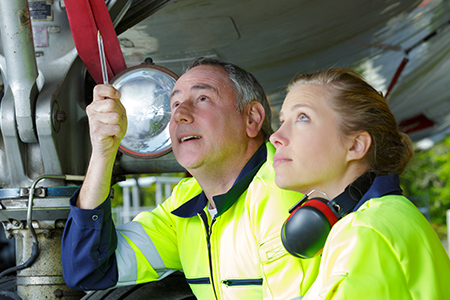 En manlig och en kvinnlig flygtekniker inspekterar flygplan i flygplansverkstad 